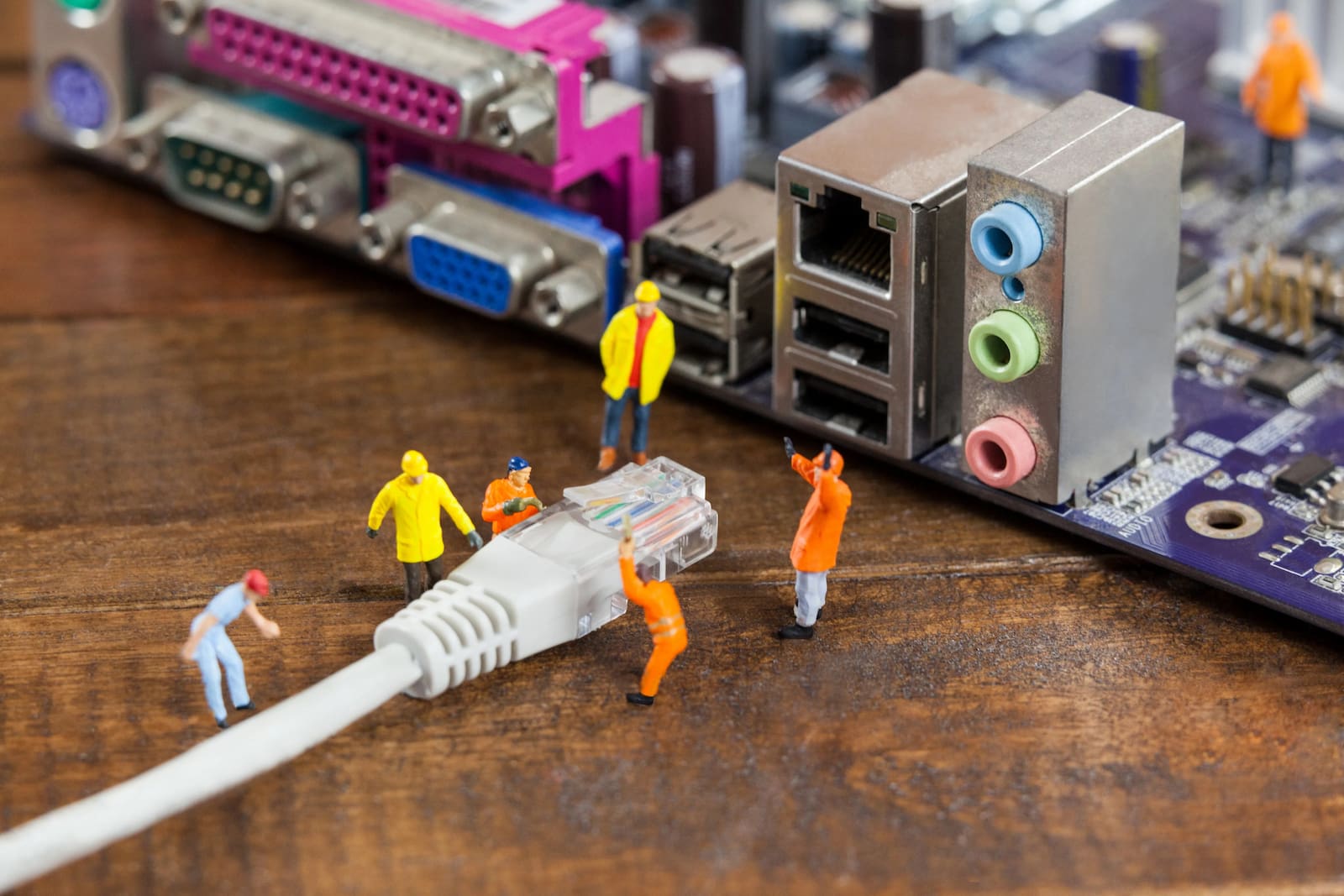 Miniature technicians connecting a network cable to a computer
