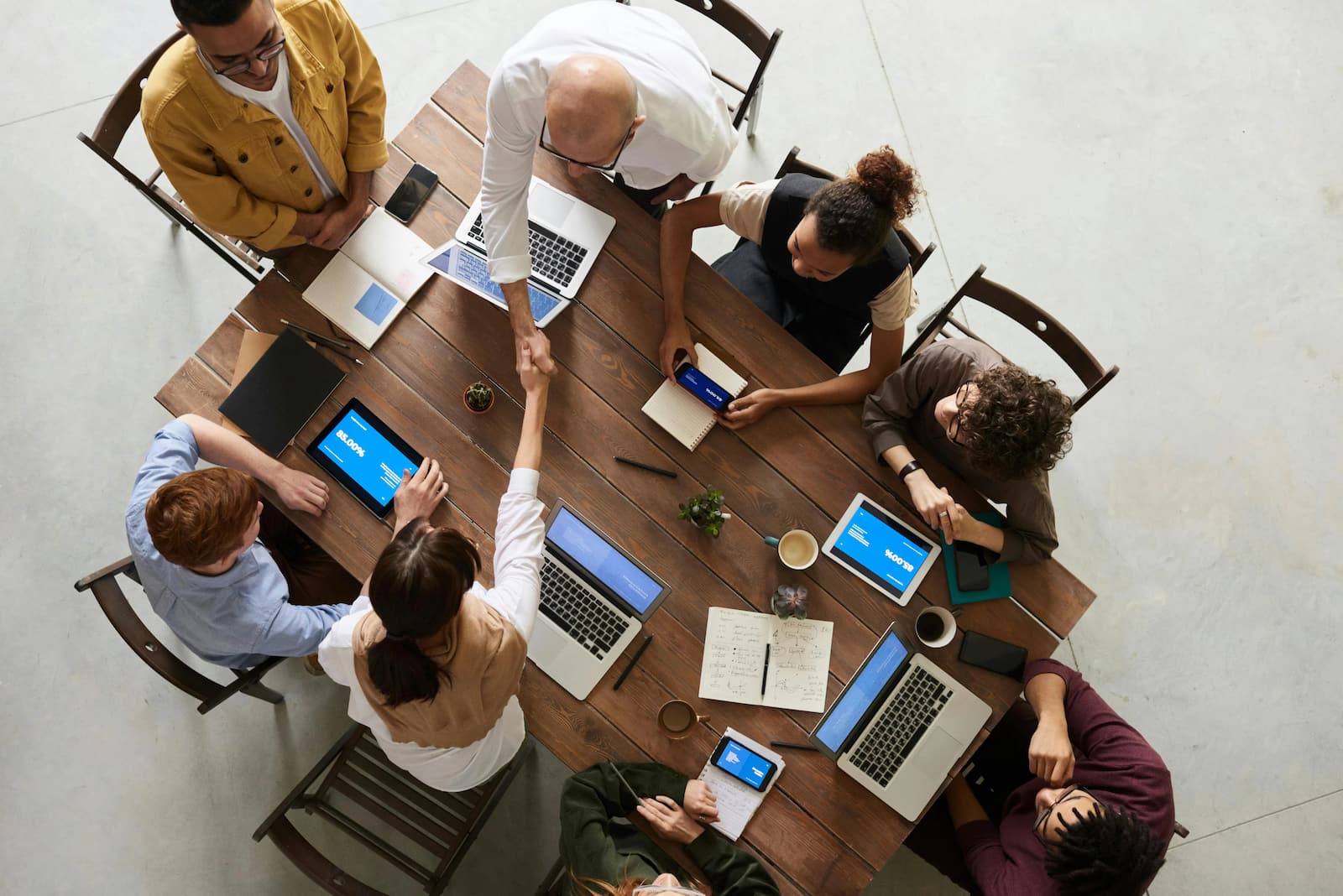 Overhead view of a team meeting around a table with laptops